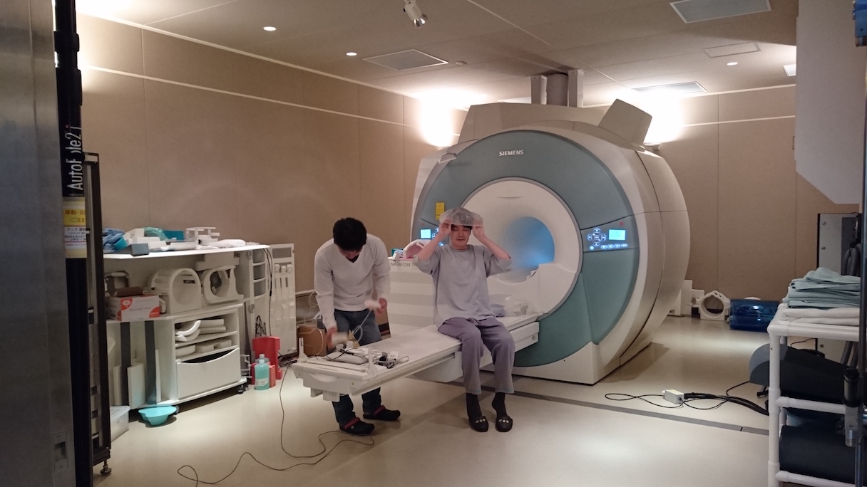 「NeuroAI? D-Planner」の脳活動計測を前に、fMRI(機能的MRI)内での動画視聴に備えて準備する被験者 ?NICT・CiNet