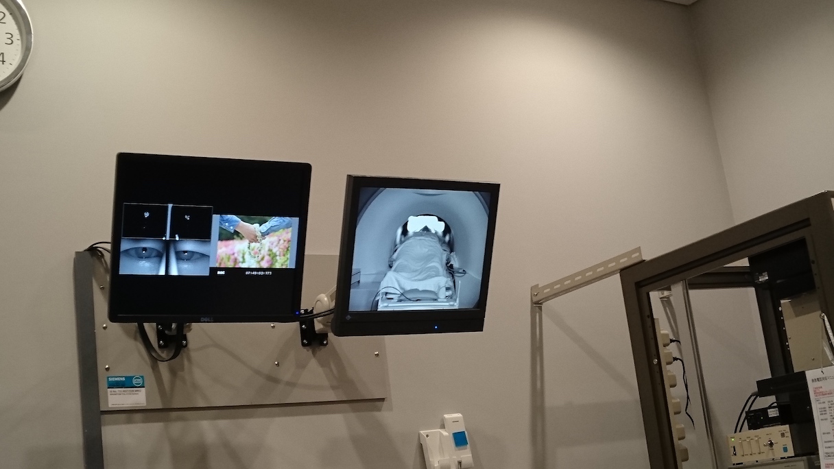 「D-Planner」による脳活動計測の一コマ。fMRI(機能的MRI)内の被験者の様子、視聴中の動画、脳内の活動状況などがモニターに映し出されている?NICT・CiNet