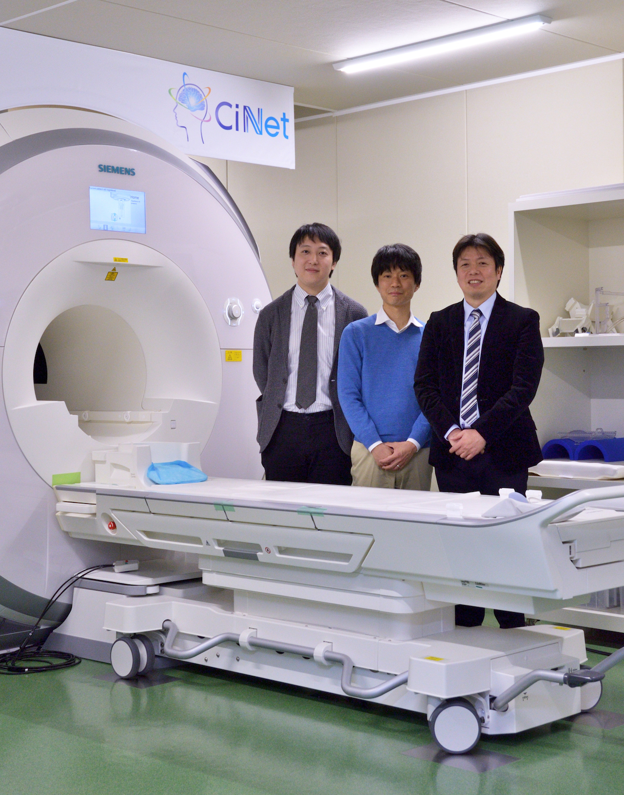 CiNetのfMRIと、「NeuroAI? D-Planner」の開発チーム。左から、茨木拓也(NTTデータ経営研究所)、西本伸志博士、矢野亮(NTTデータ) (写真提供:情報通信研究機構 脳情報通信融合研究センター ?Takashi Matsui / DIAMOND Online)